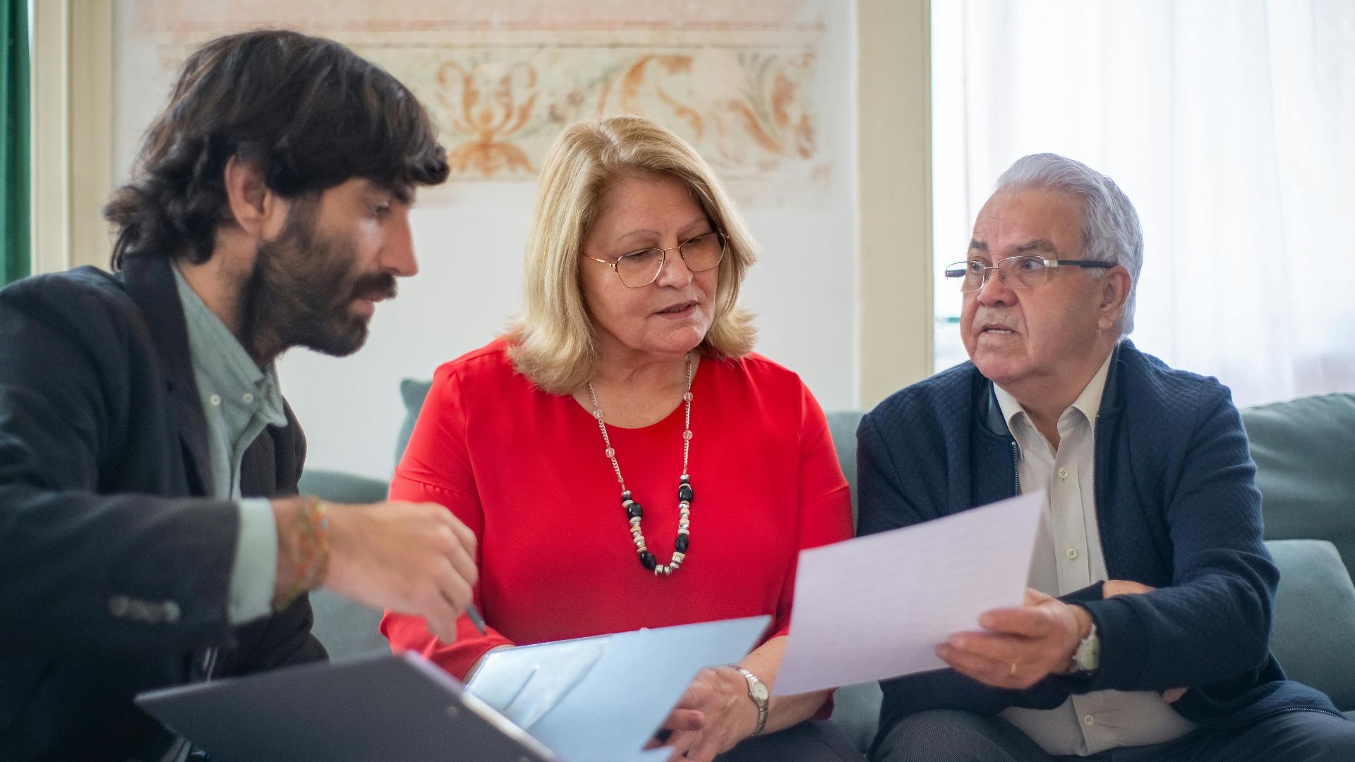 Senior couple consulting with a professional advisor, discussing documents indoors.