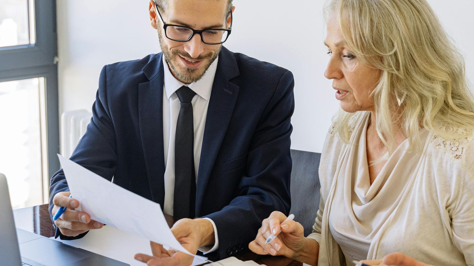 Two business professionals reviewing financial documents and graphs during a meeting.