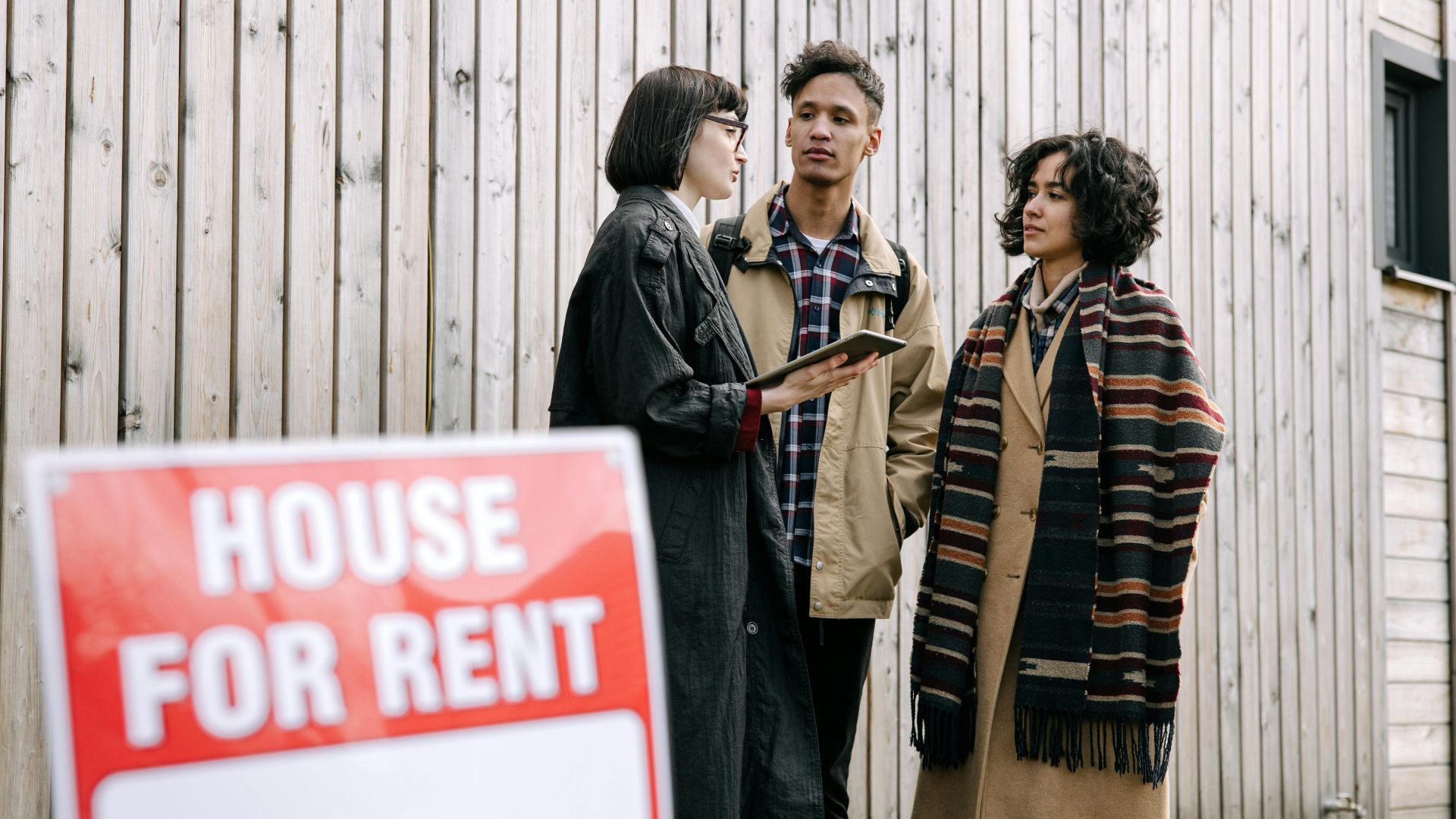An interracial couple meets with a real estate agent to inquire about a house for rent.