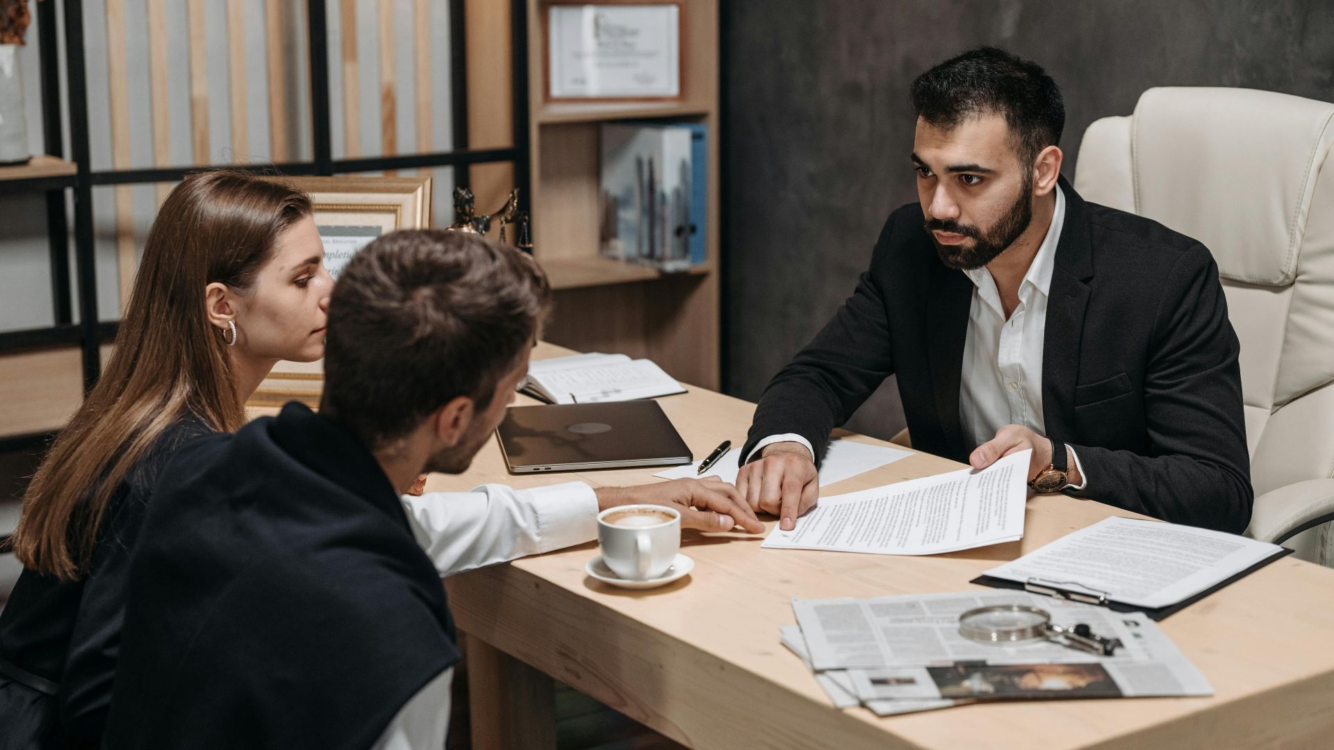 Lawyer discussing legal documents with clients at office desk.