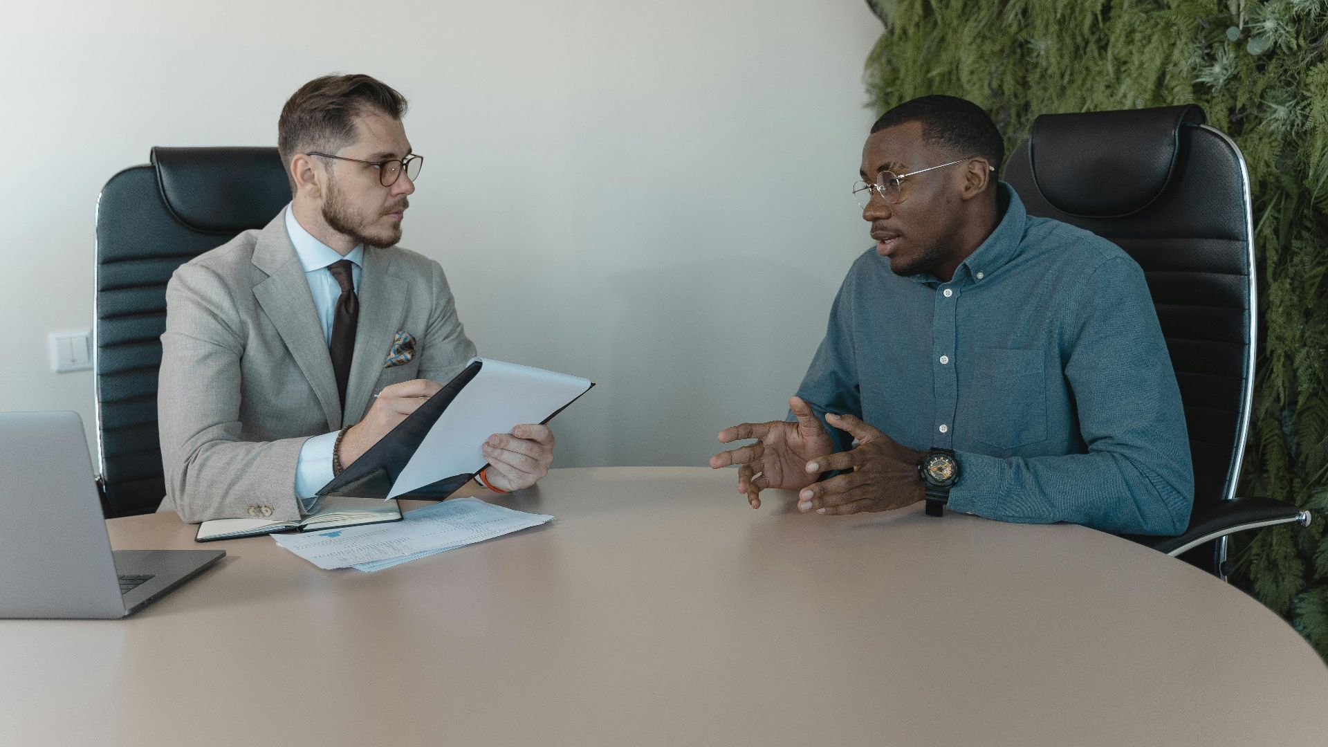 Two businessmen engaged in a discussion during a job interview in a contemporary office environment.