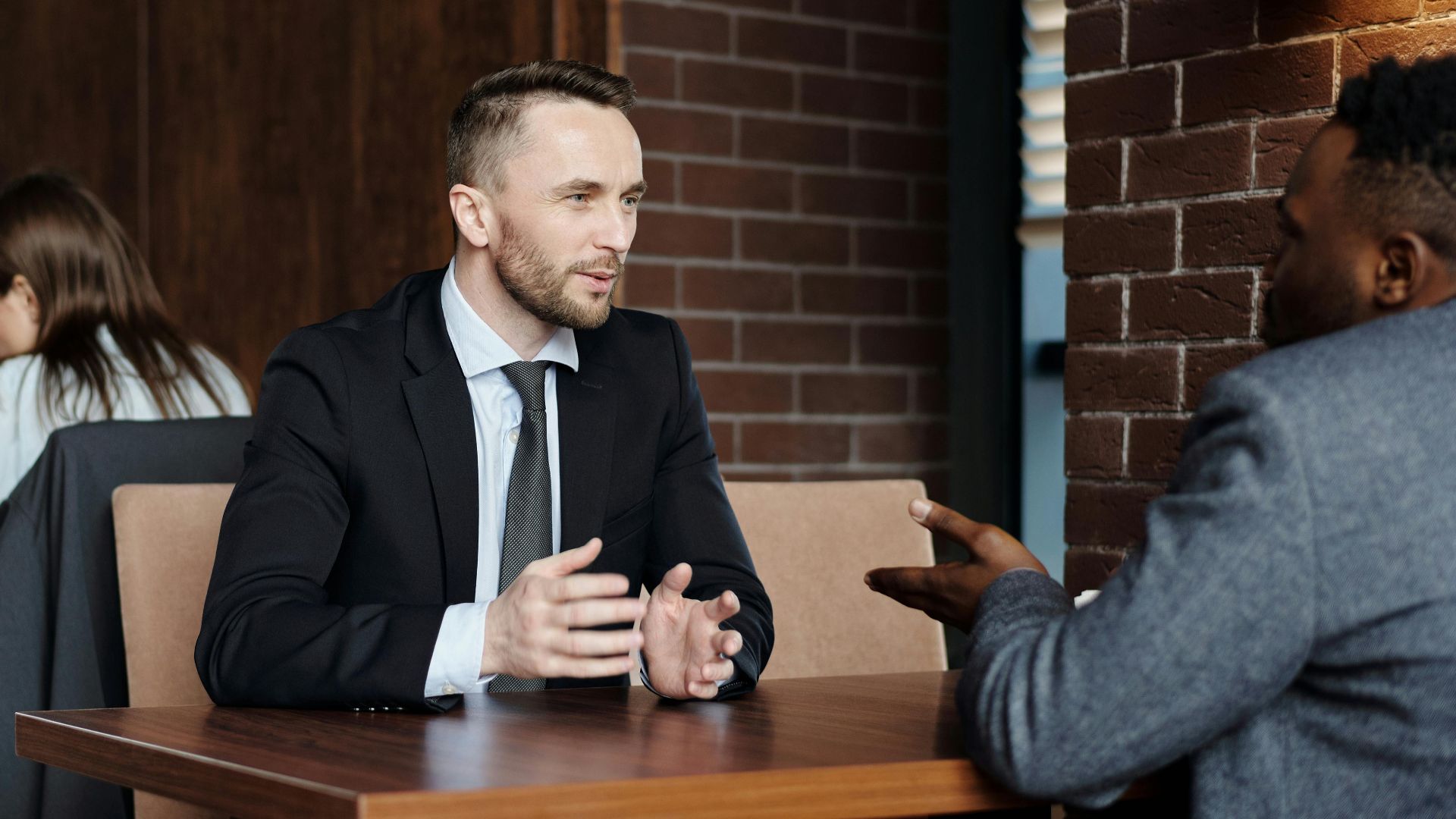 Businessmen engaged in a professional conversation in a stylish café setting.