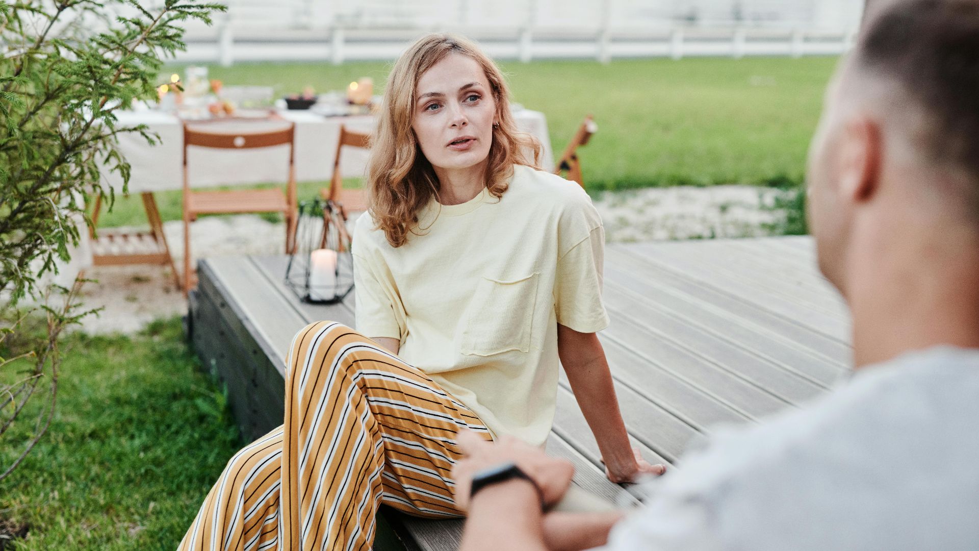 A couple engaged in a thoughtful conversation outdoors in a relaxed garden setting.
