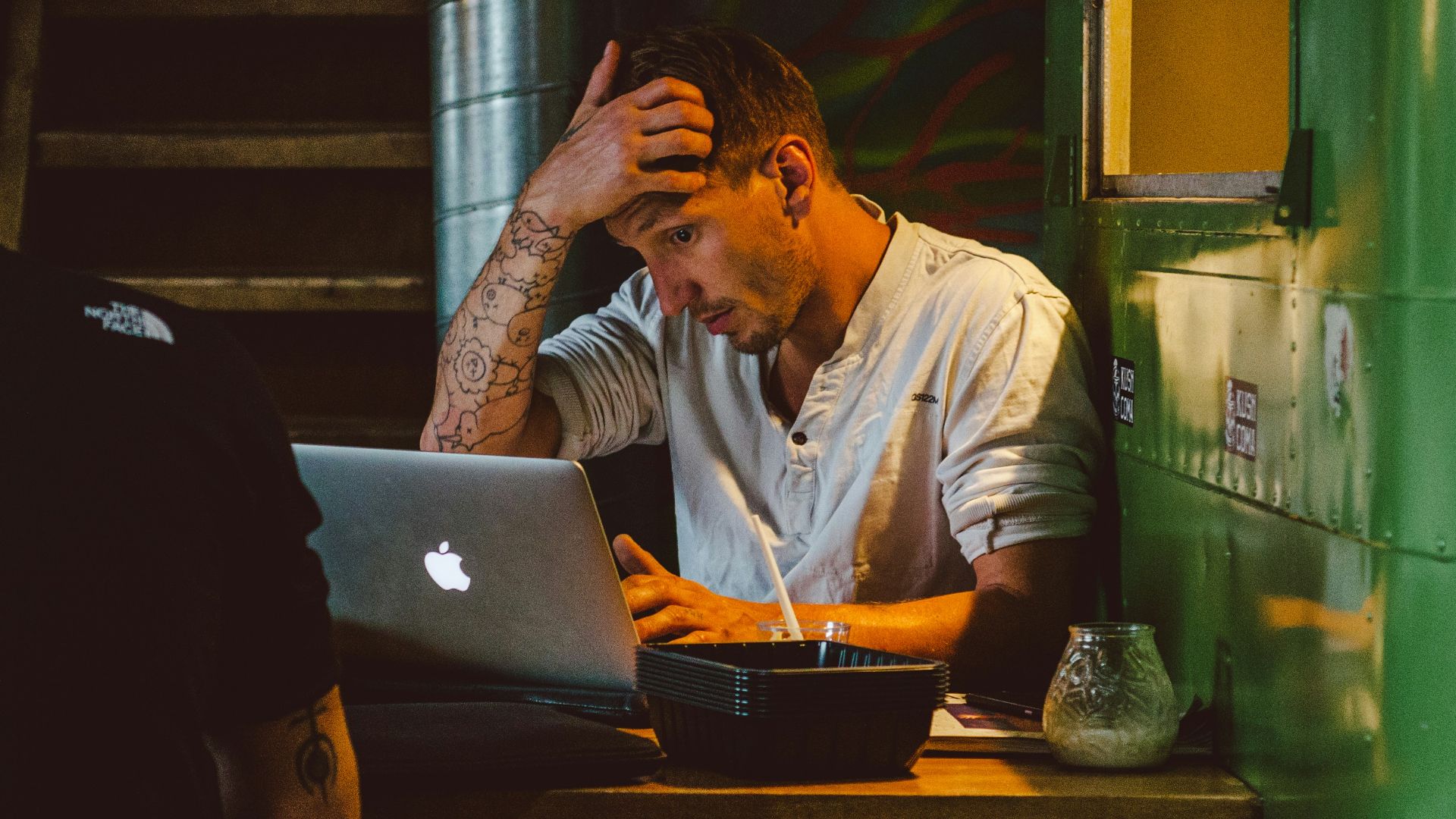 man in front of silver MacBook while scratching his head
