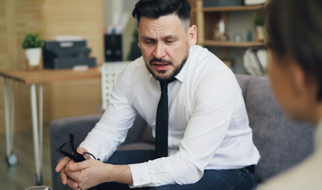 a man in a white shirt and tie sitting on a couch