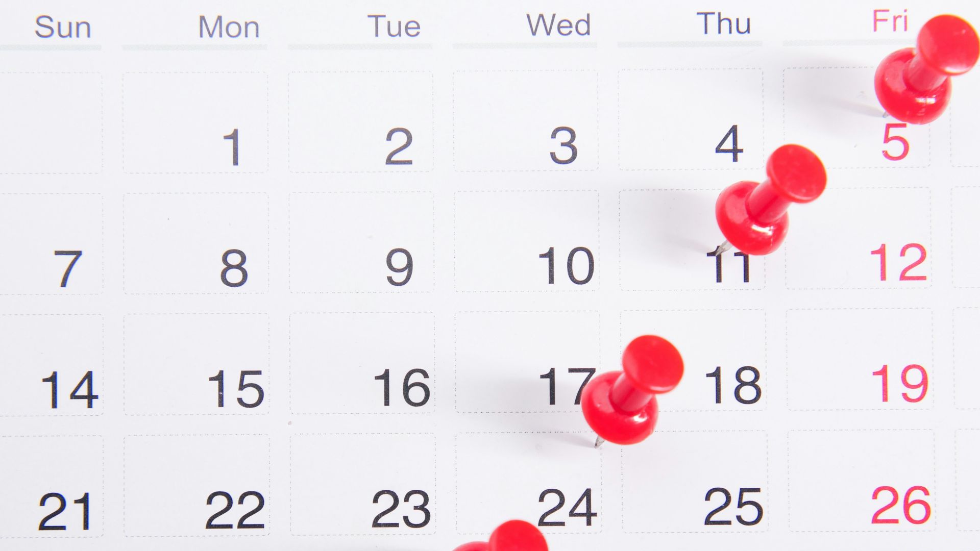 a calendar with red push buttons pinned to it