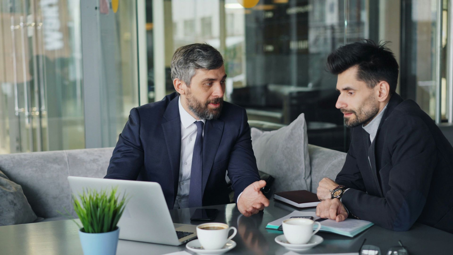 a couple of men sitting at a table in front of a laptop