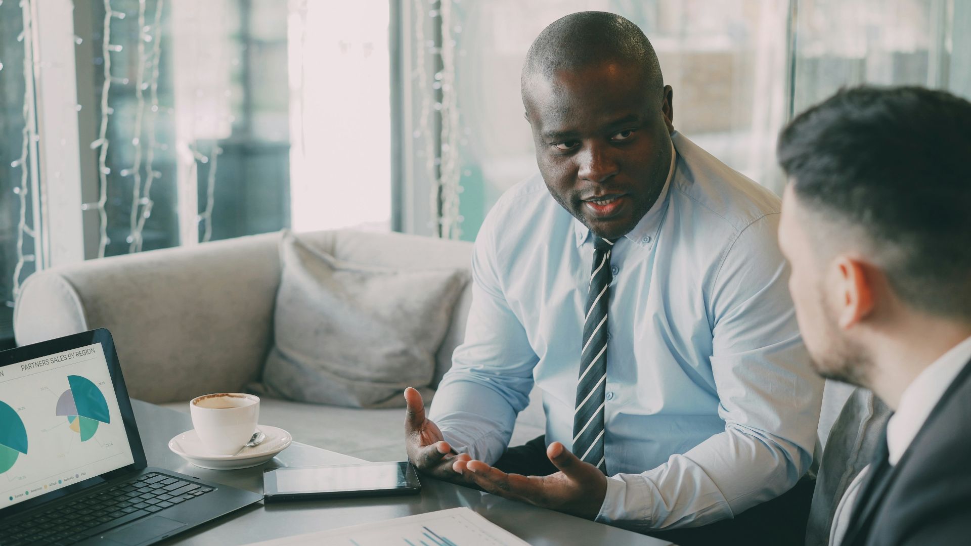 Two businessmen discussing charts in a cafe.