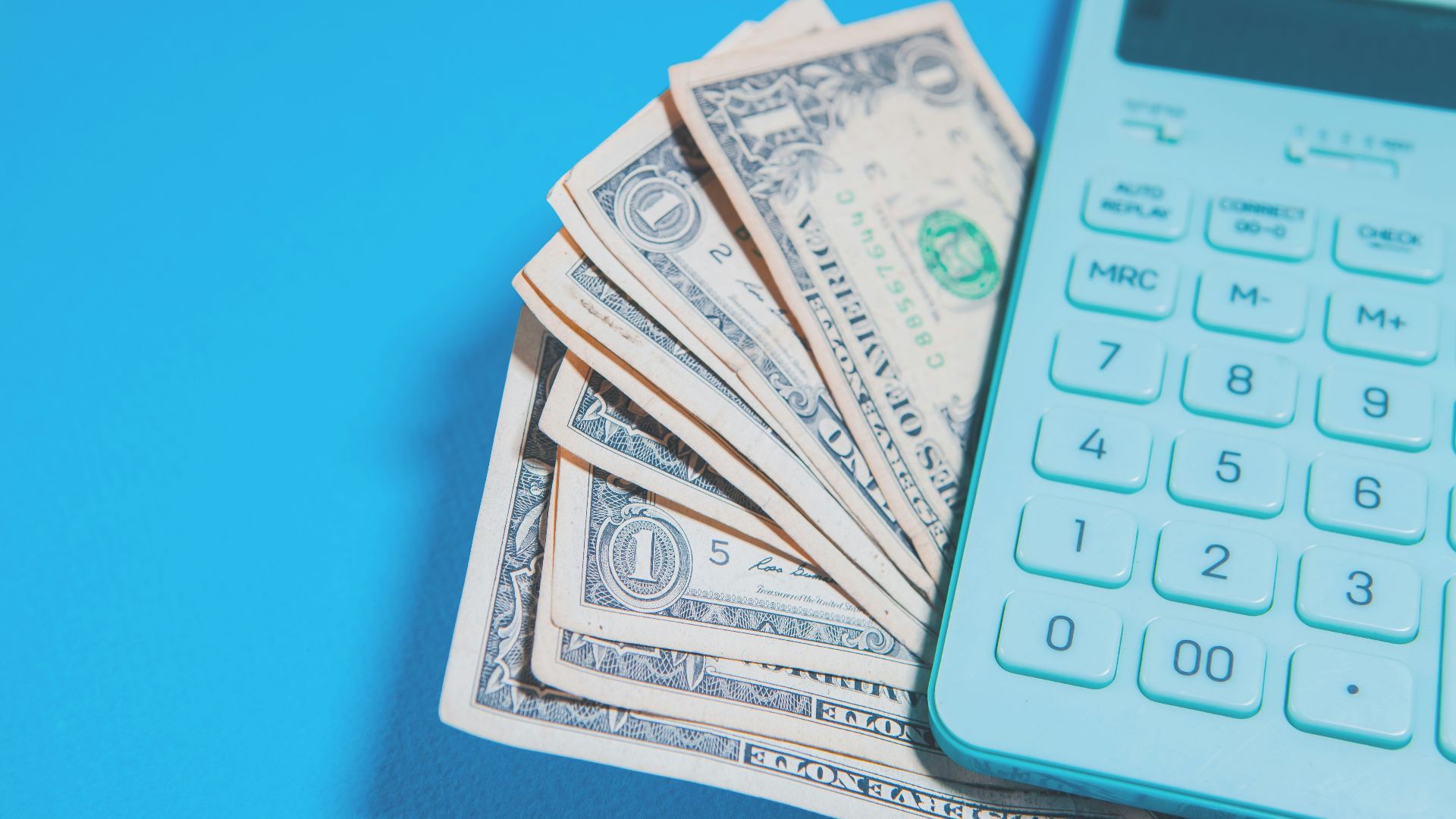 Us dollar bills and a calculator on blue background