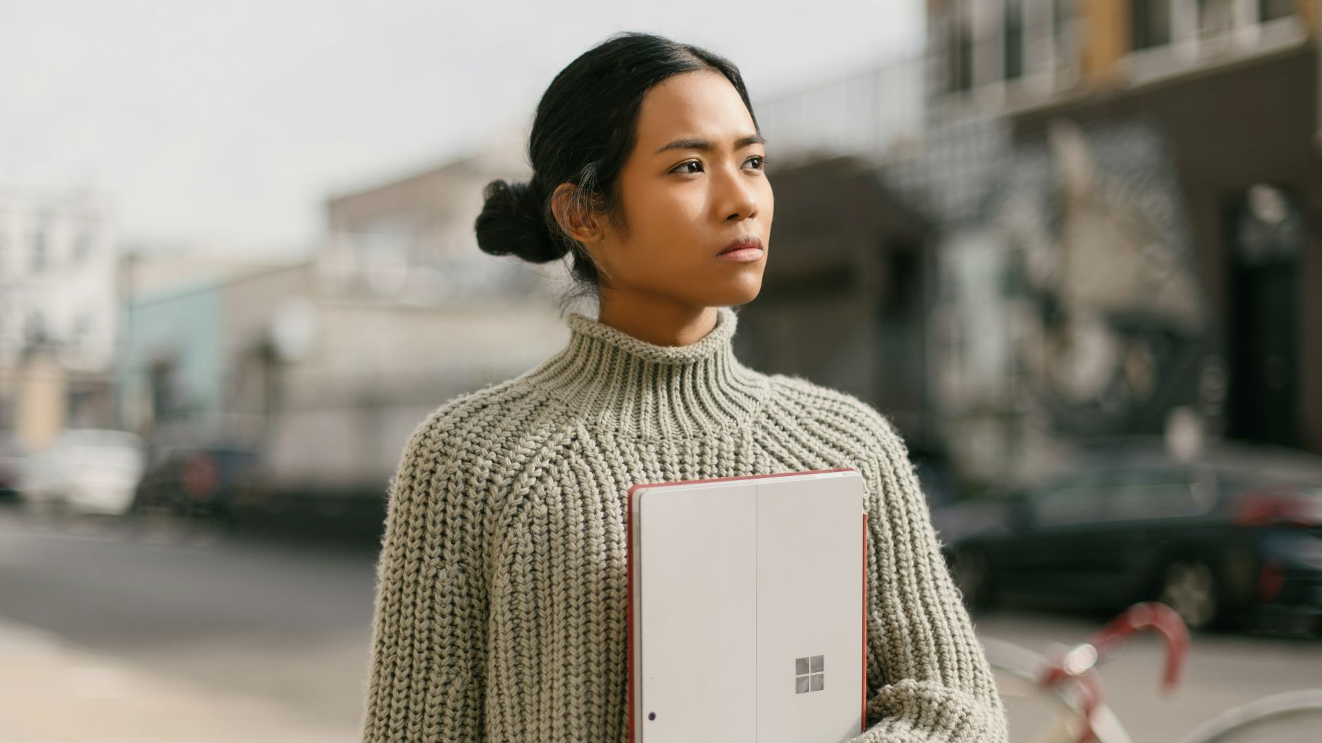 a woman standing on a sidewalk holding a laptop