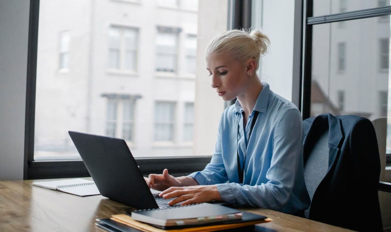 Serious woman typing on laptop in workspace