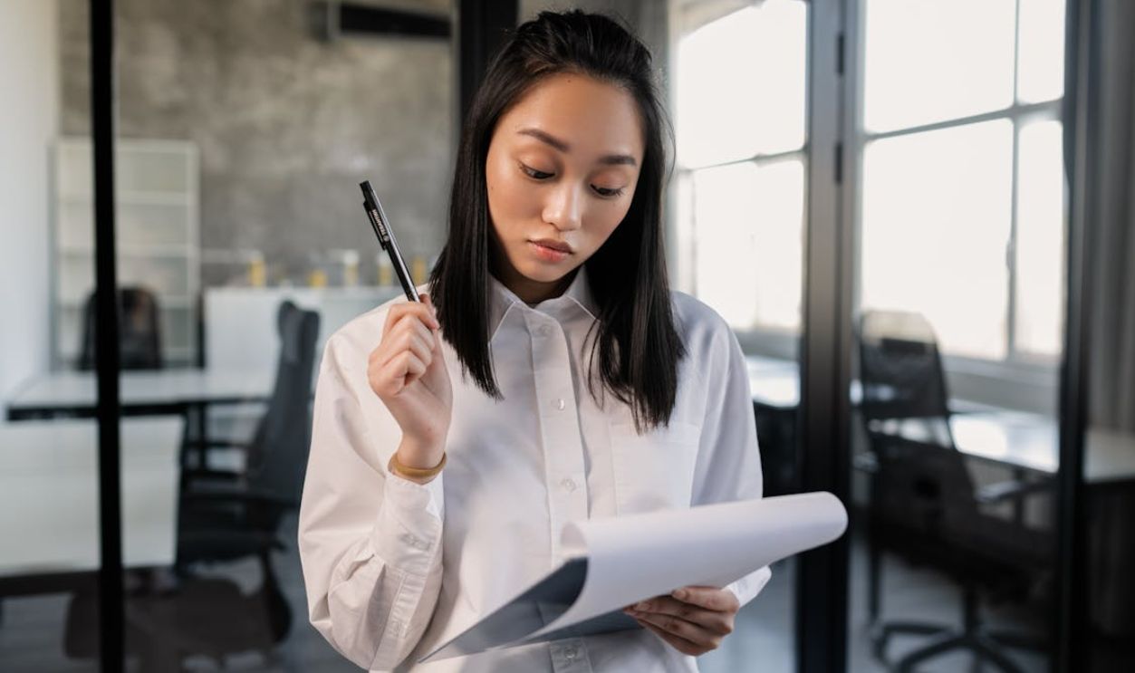 Photo of a Woman Holding a Pen and a Clipboard
