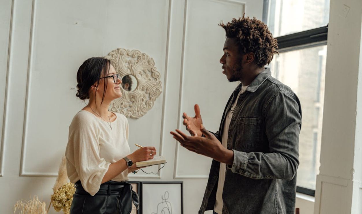 Man in Black Jacket Standing Beside Woman in White Shirt