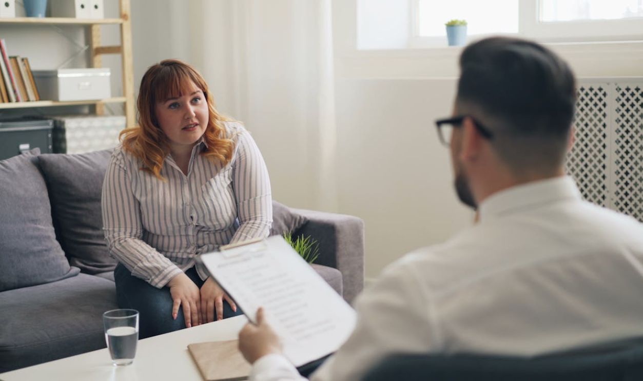 A woman sitting on a couch talking to a man