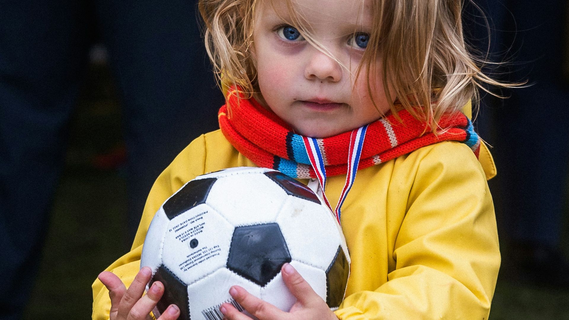 A little girl holding a soccer ball in her hands