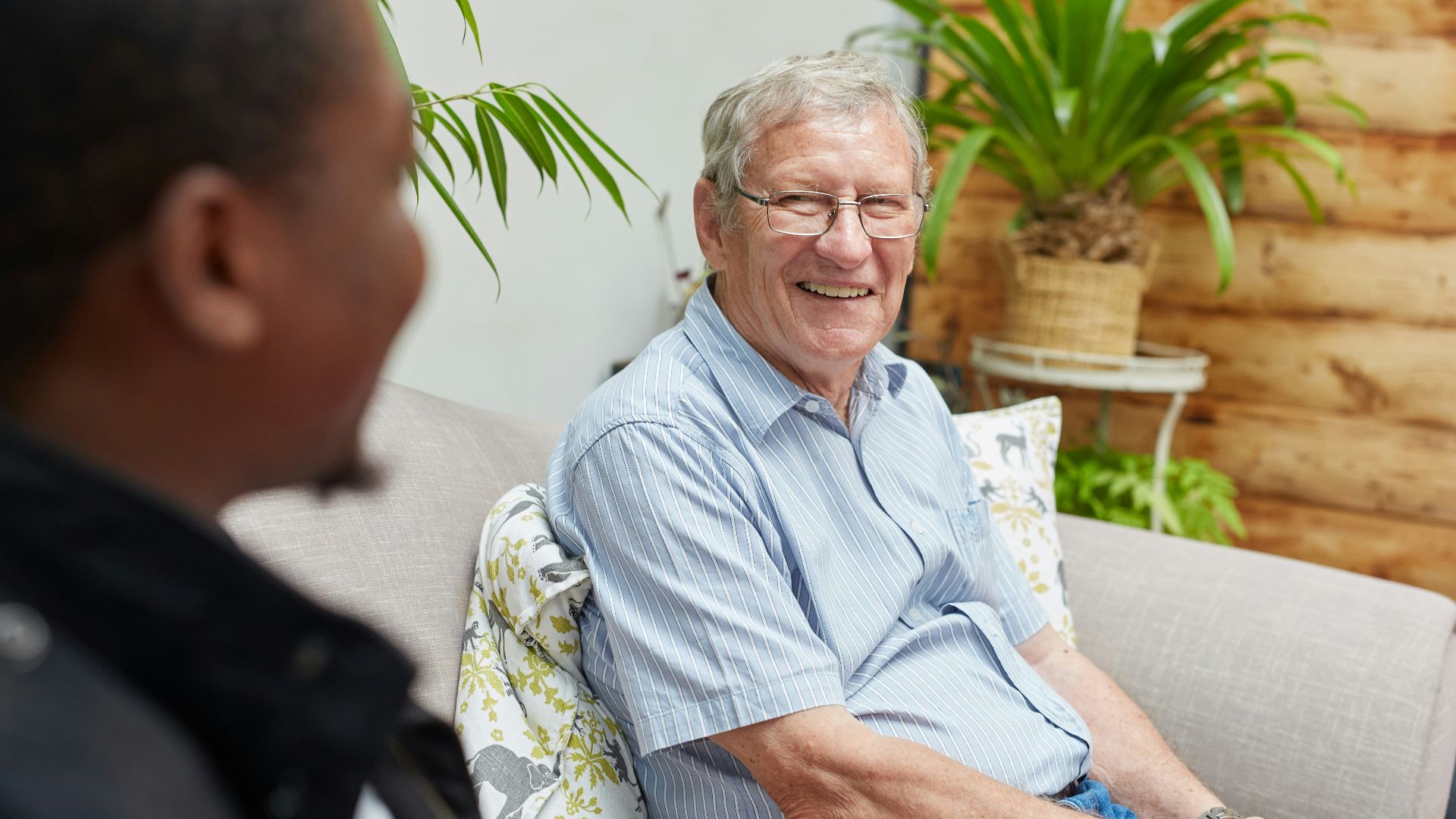 a man sitting on a couch talking to another man