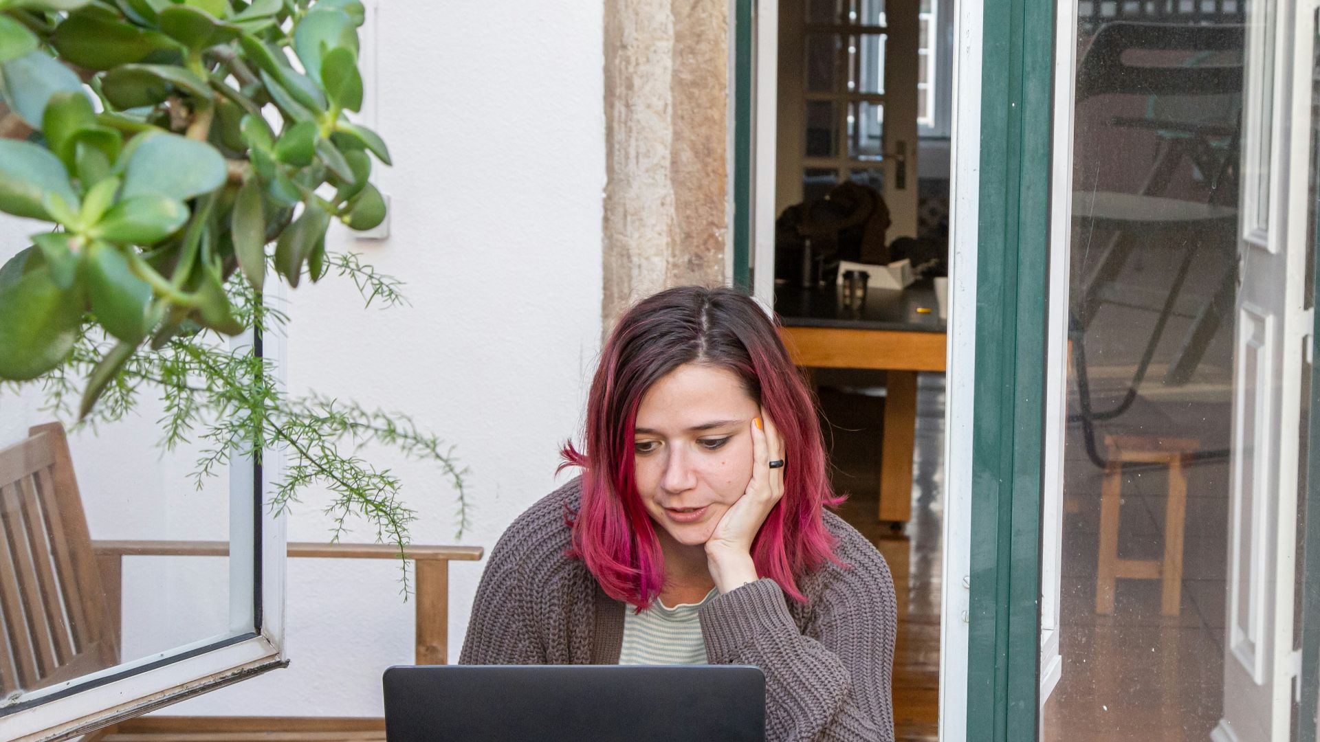 a woman with pink hair is looking at a laptop