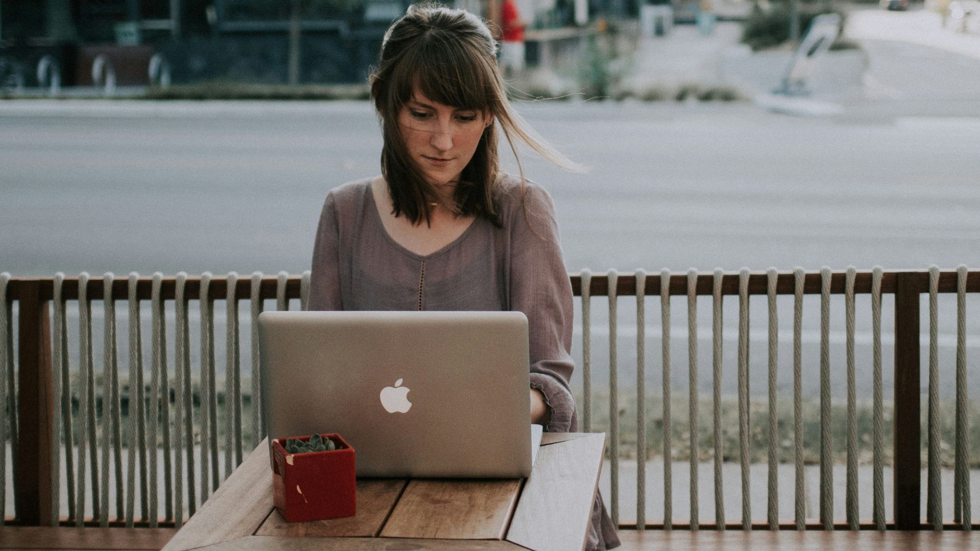 woman in gray shirt sitting on bench in front of MacBook