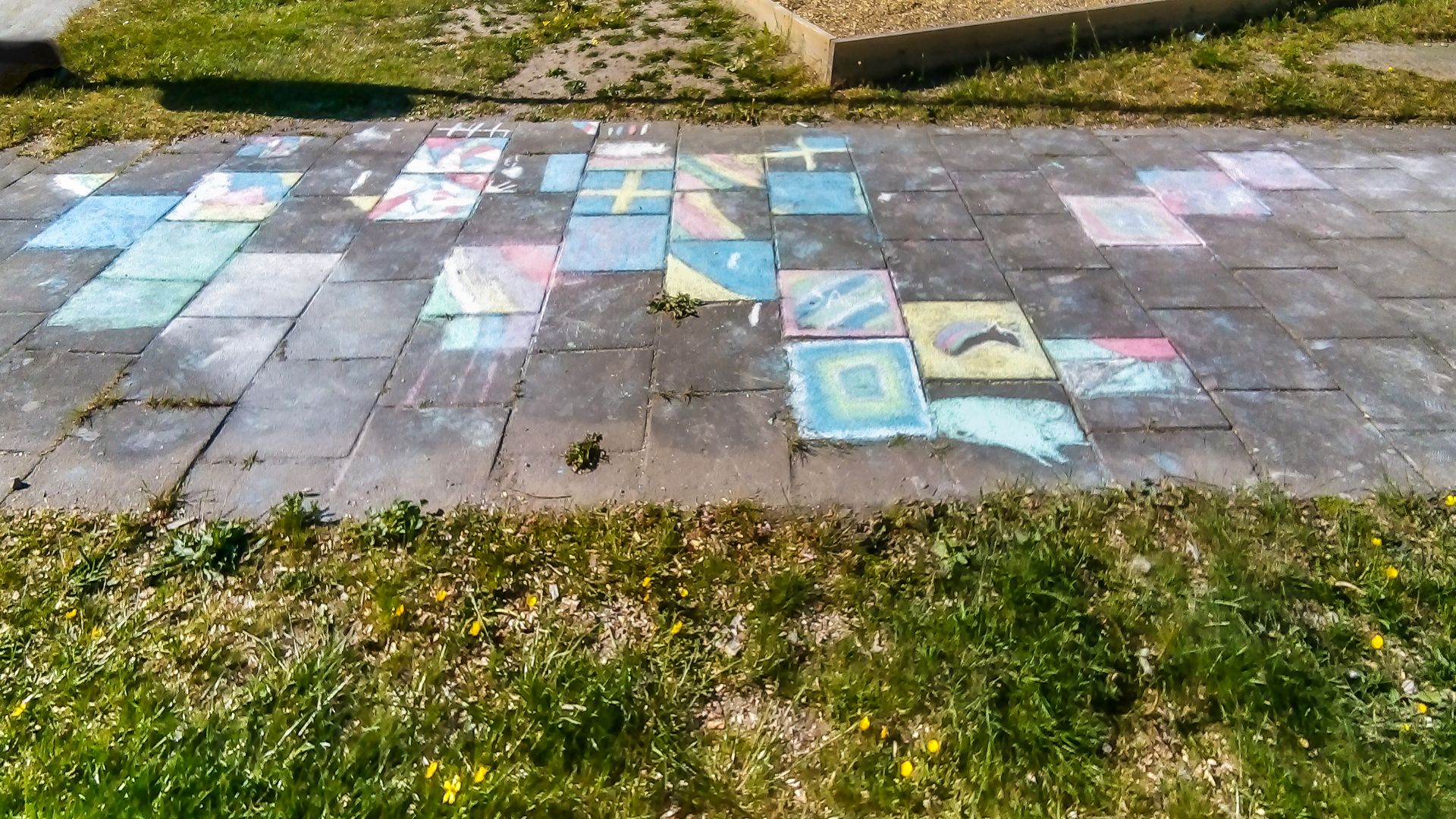 Sidewalk chalk drawings on concrete pavers in a playground in Brastad, Lysekil Municipality, Sweden.
