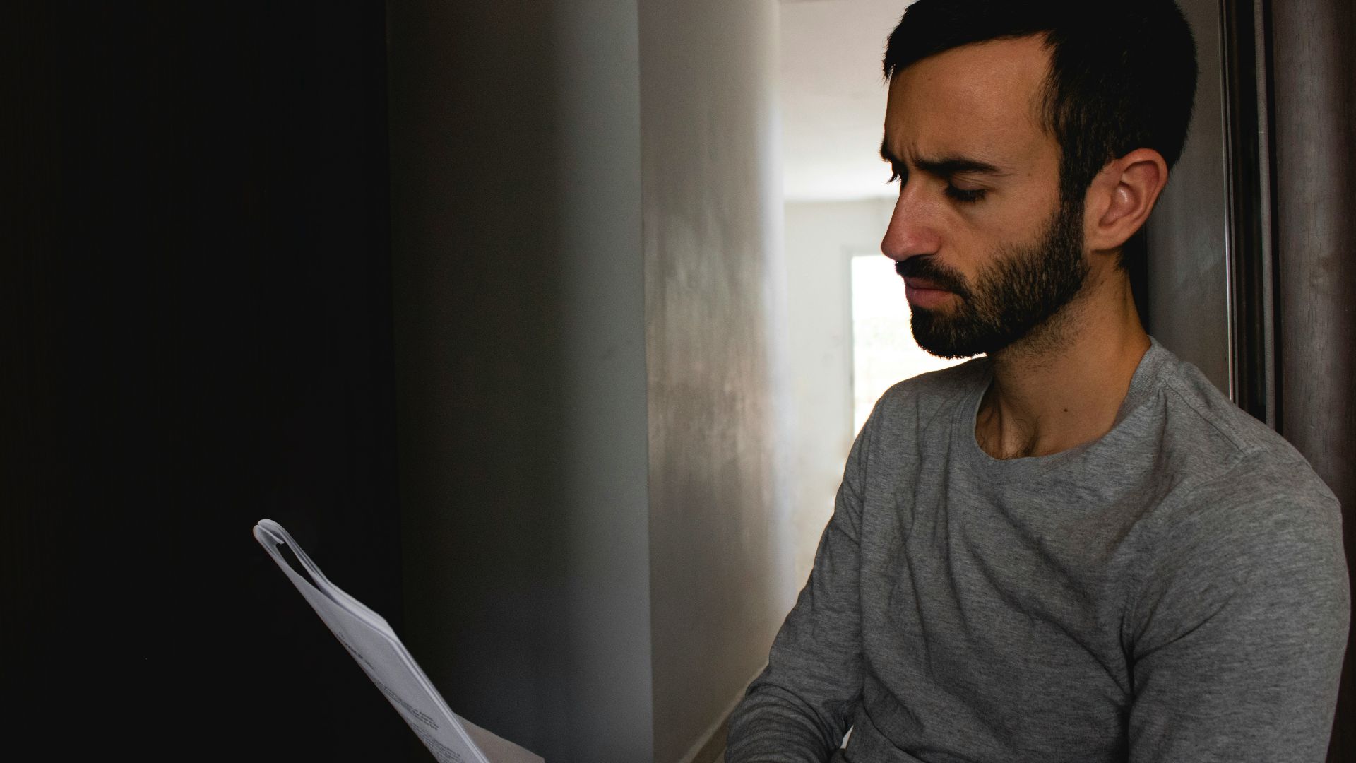 man in gray crew neck shirt holding white printer paper