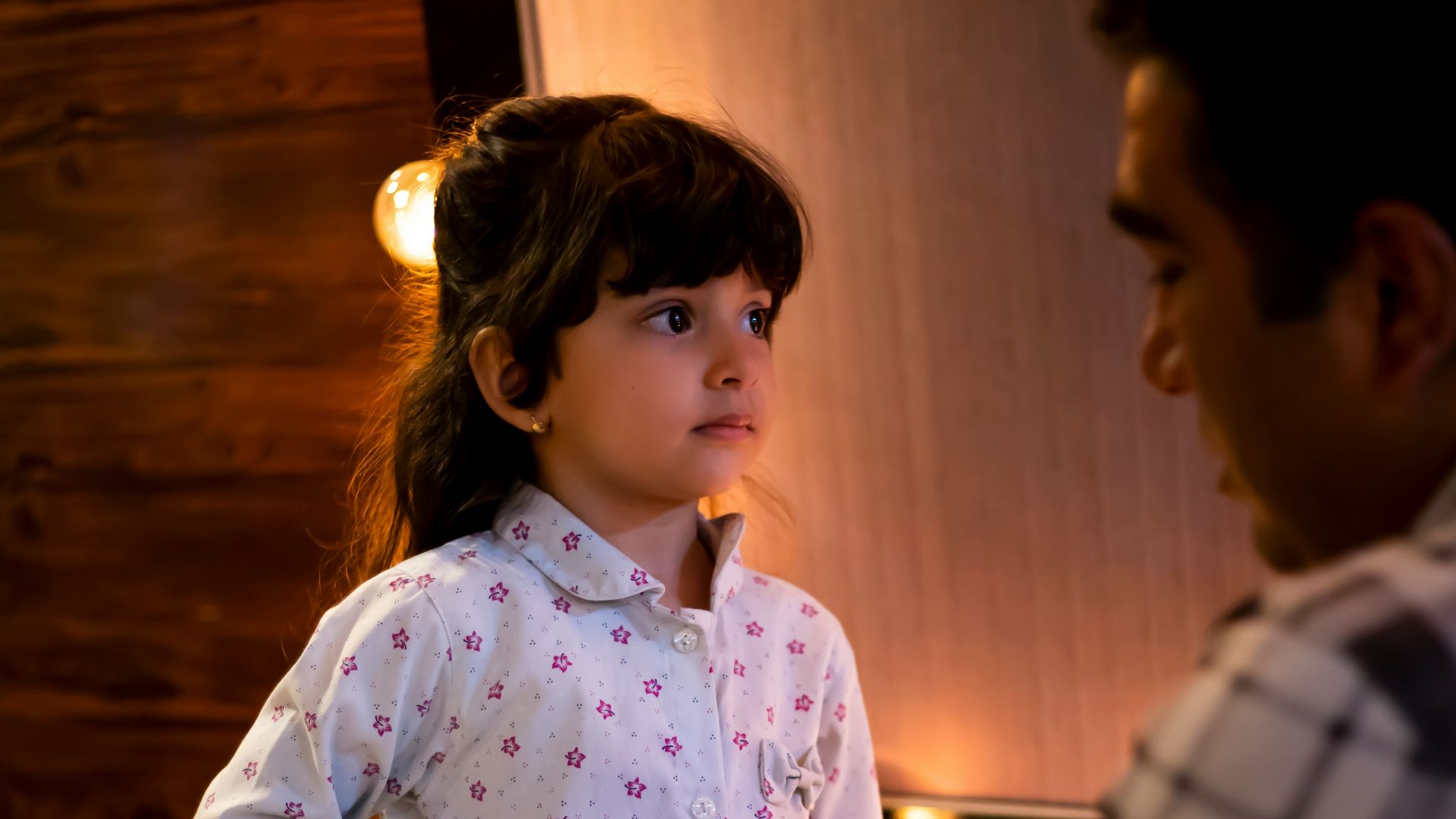 A man adjusts a child's shirt in a room.