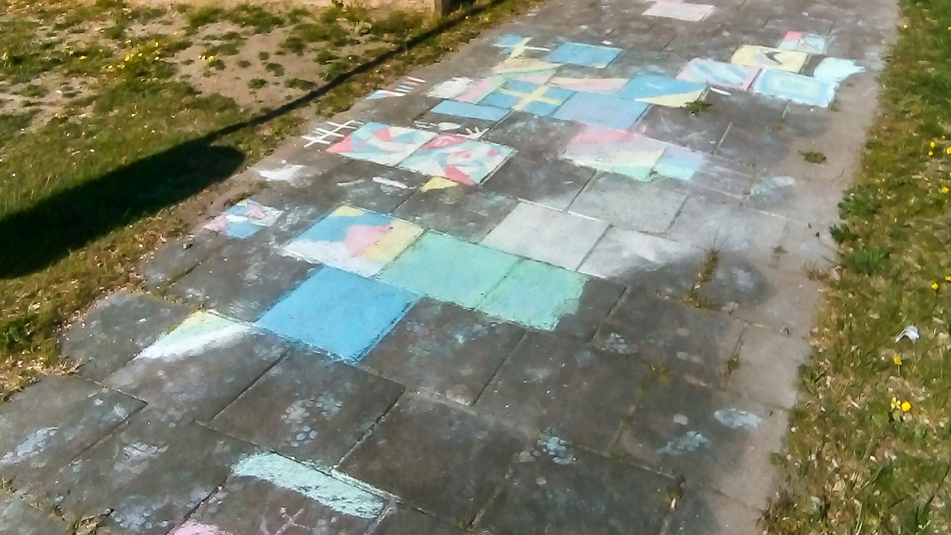 Sidewalk chalk drawings made by kids on concrete pavers in a playground in Brastad, Lysekil Municipality, Sweden.