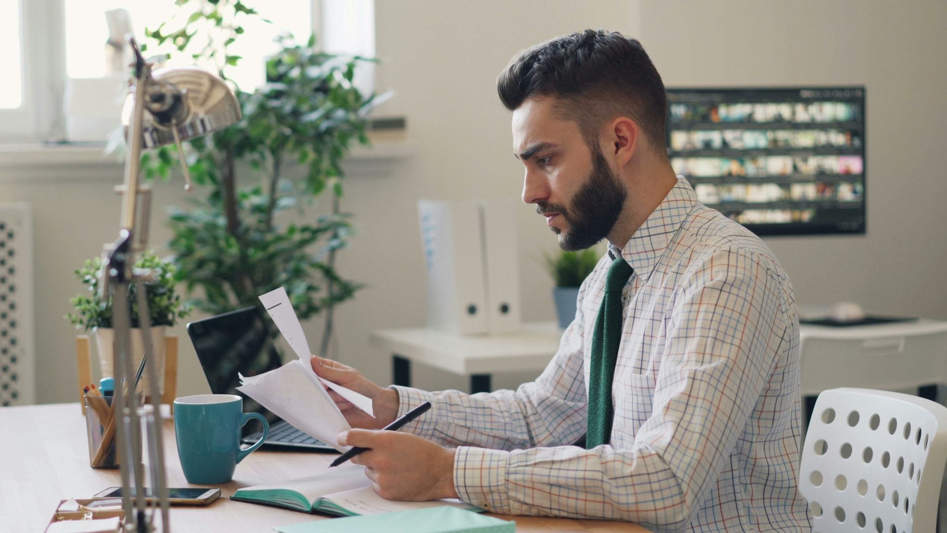 a man sitting at a desk with a laptop and papers