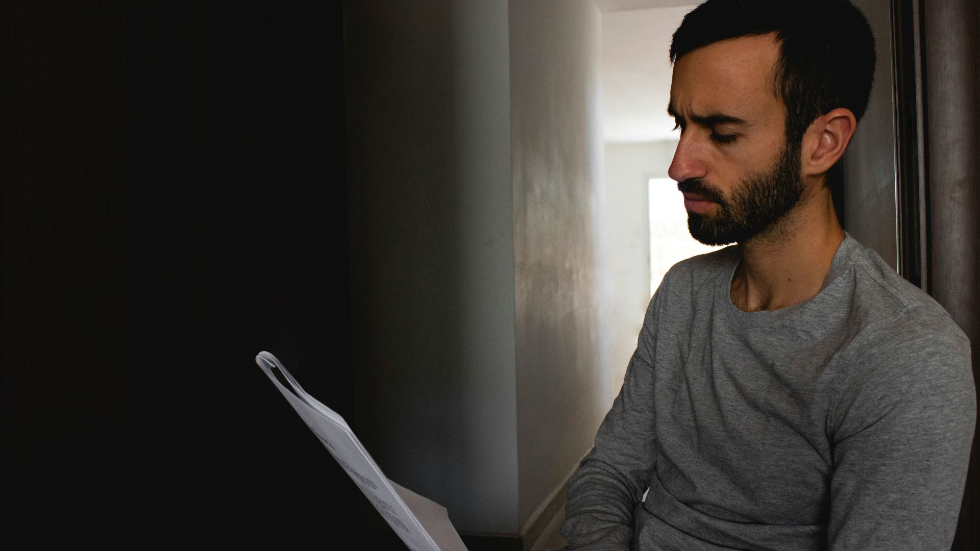 man in gray crew neck shirt holding white printer paper