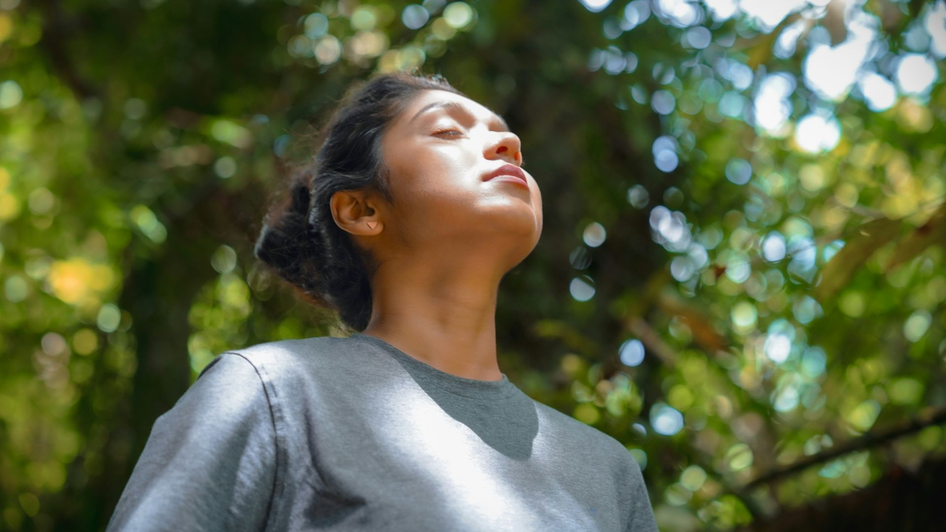 a woman standing in front of a tree with her eyes closed