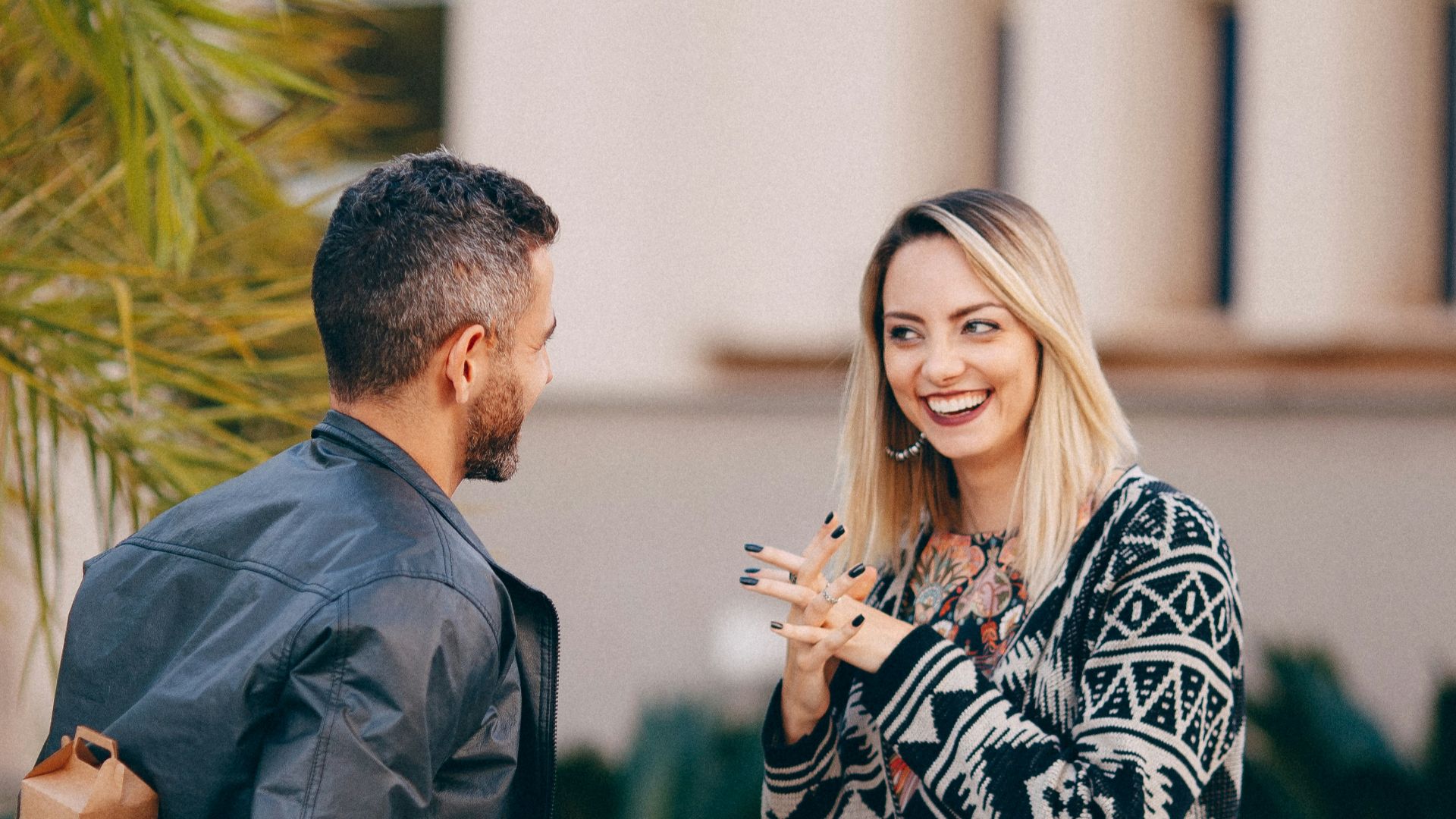 man in black suit jacket holding woman in black and white dress