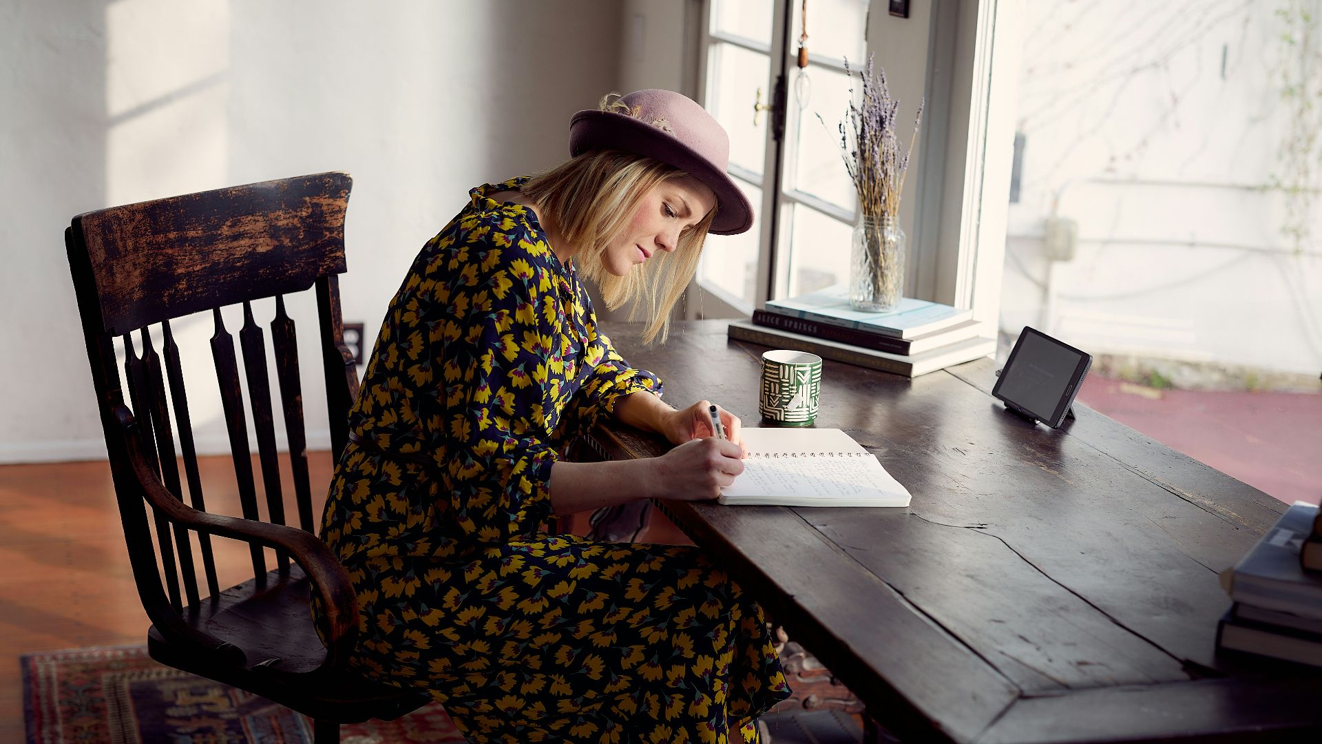 woman in yellow and black floral dress sitting on brown wooden chair