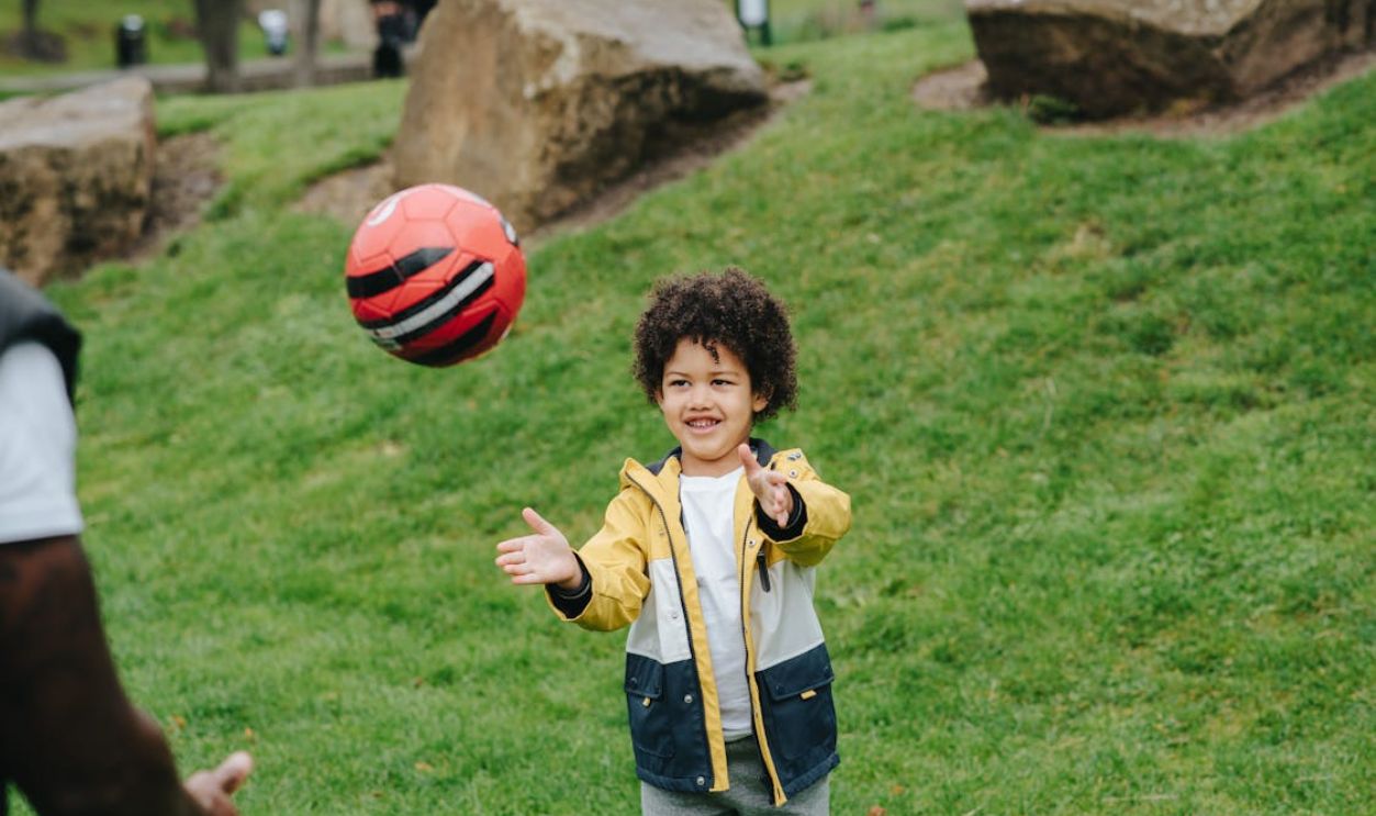 Cheerful black boy playing with ball