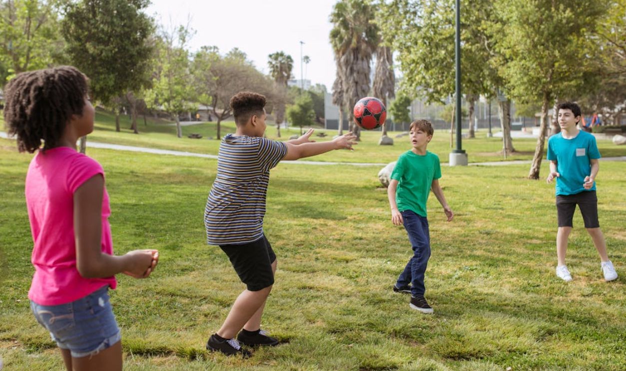 Teenagers Having Fun Playing Soccer Ball on a Park