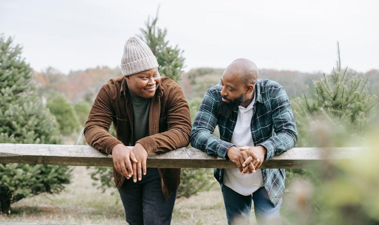 Black father talking to son in fir trees field