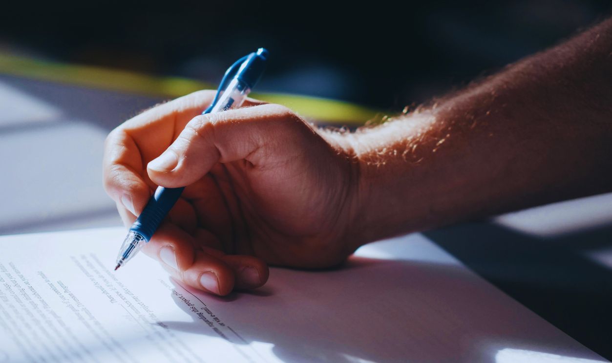 A Person Signing a Document