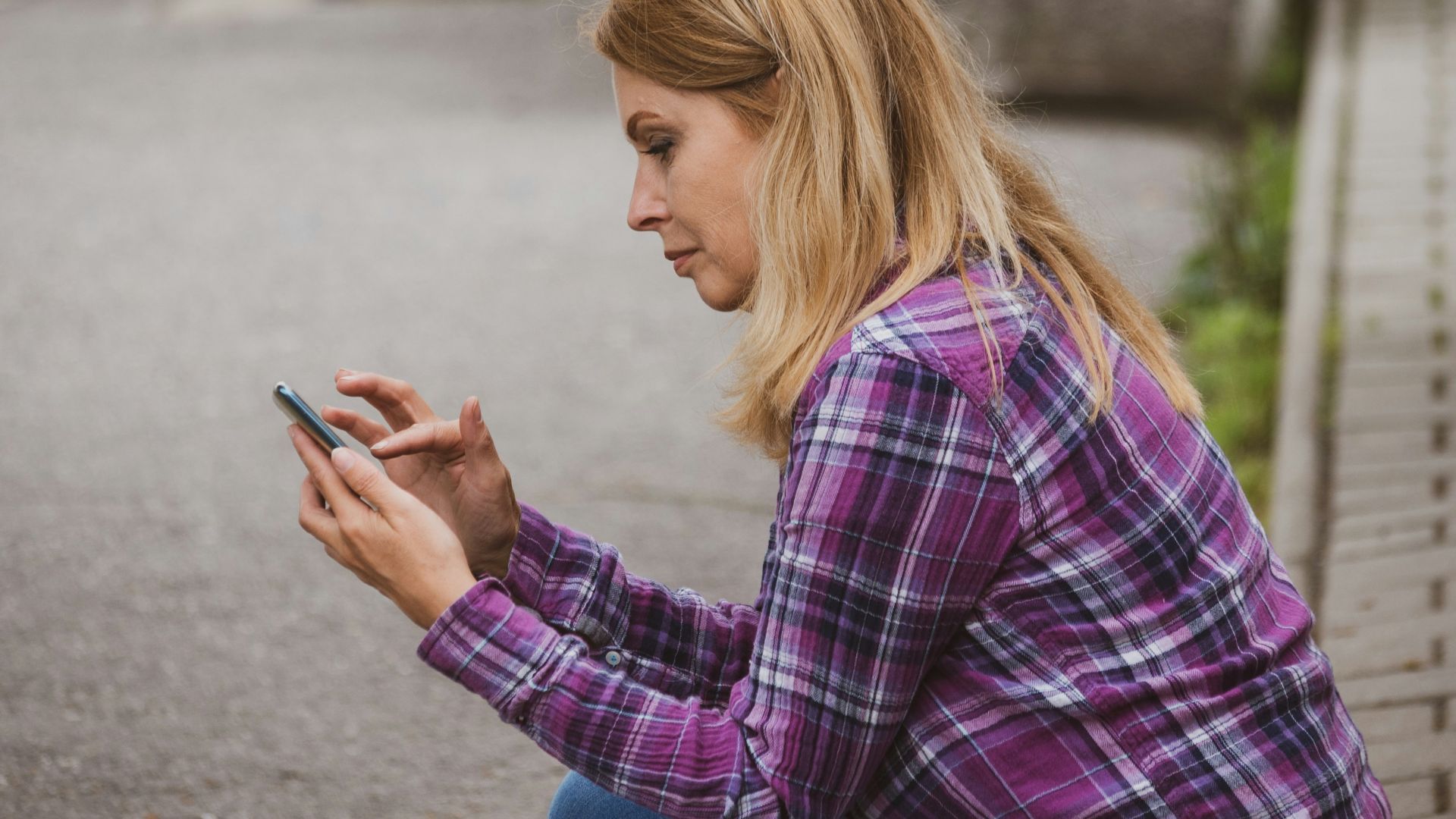 a woman sitting on the ground looking at her cell phone