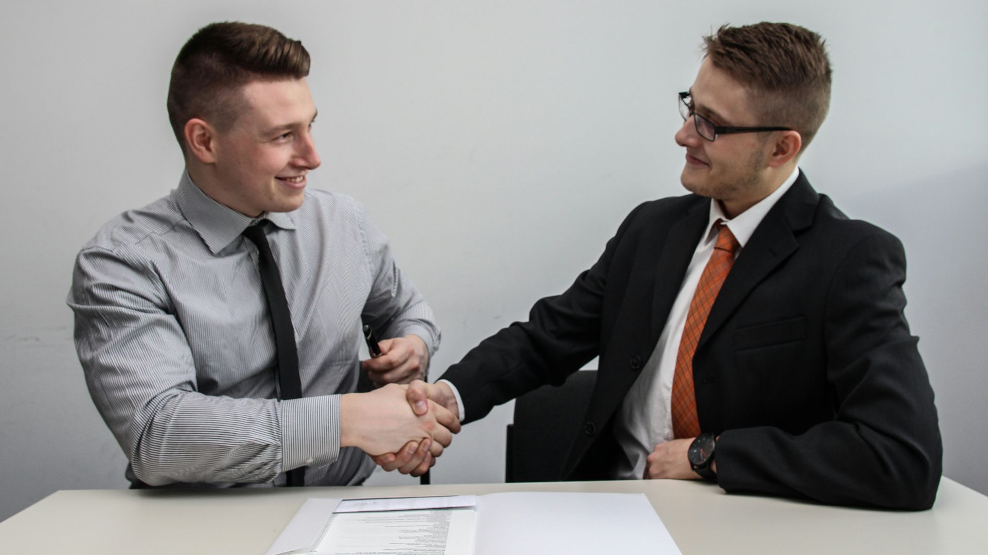 two men facing each other while shake hands and smiling