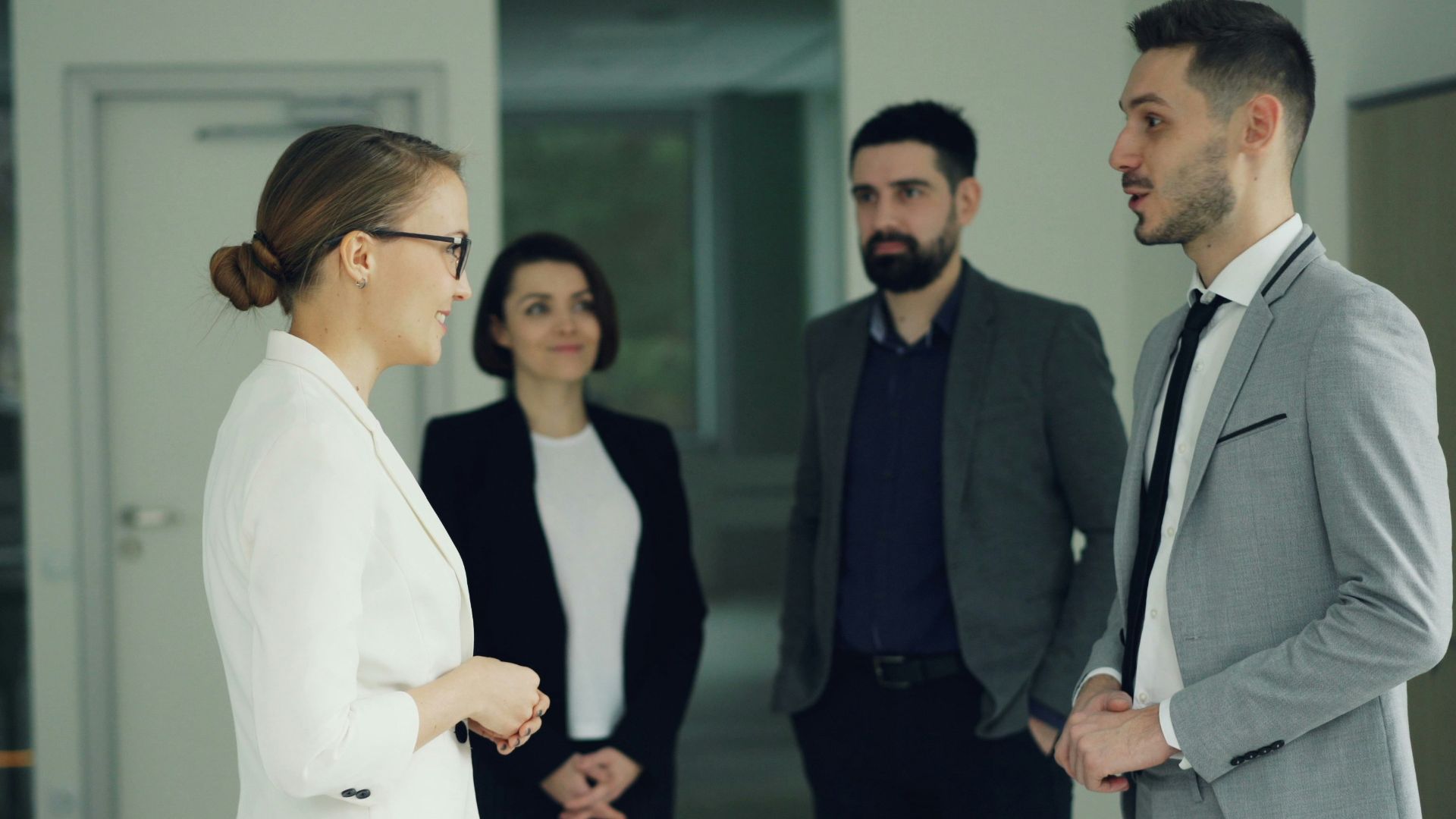 Business professionals conversing in a modern office hallway.