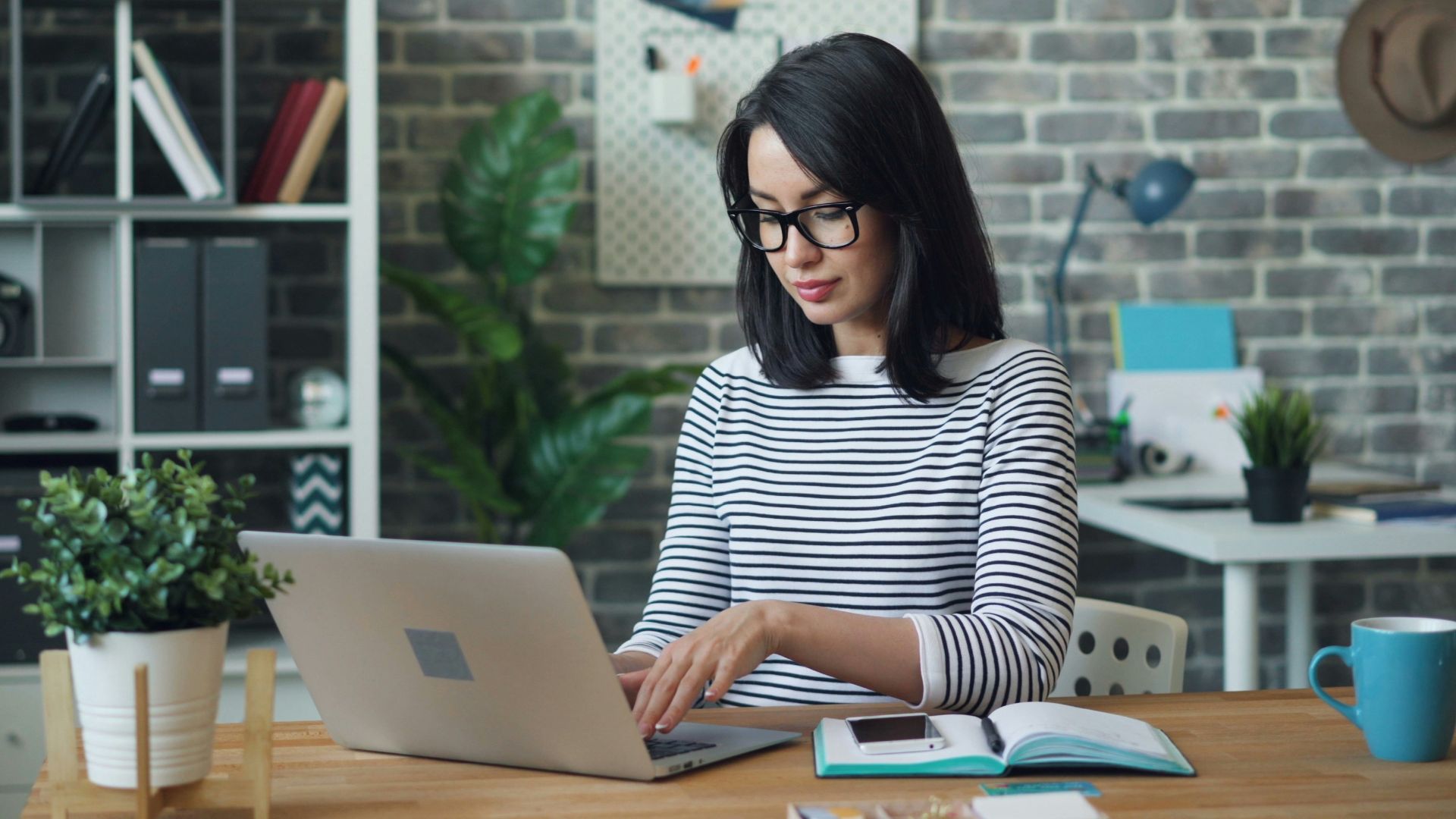 a woman sitting at a table using a laptop computer