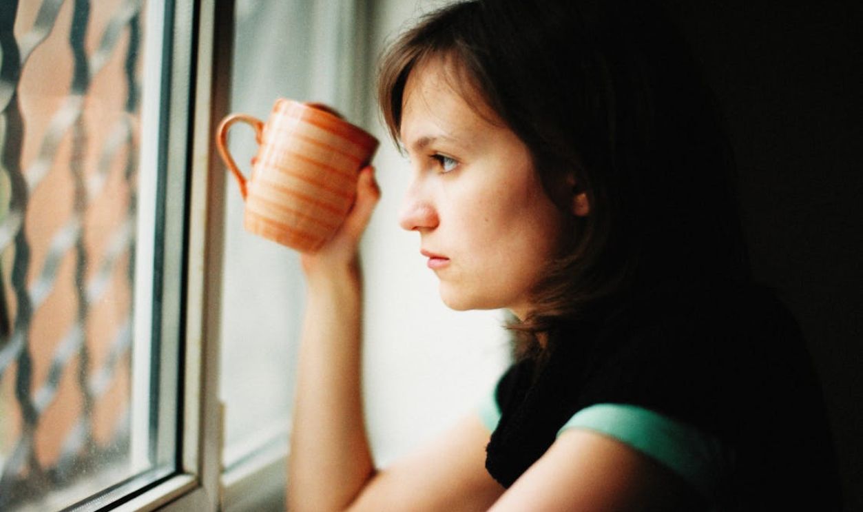 Woman with Mug Looking through Window