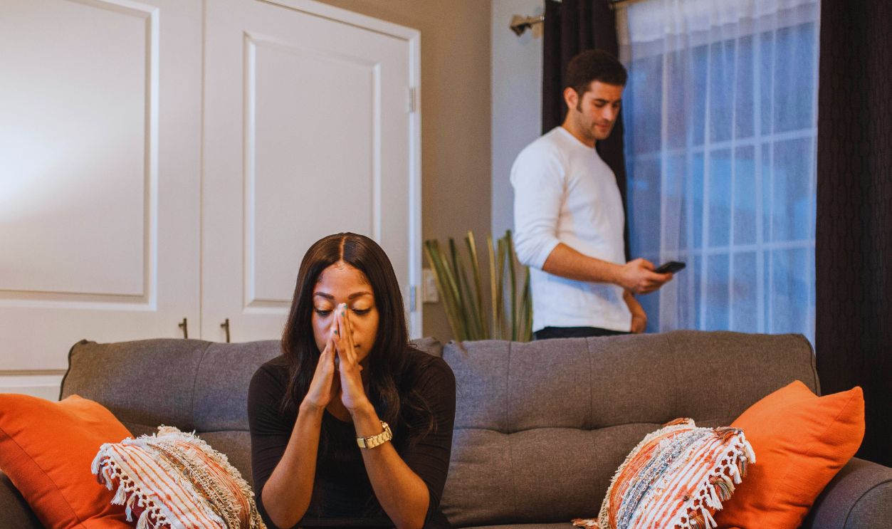 A Woman Sitting on the Sofa While a Man is Standing at the Back