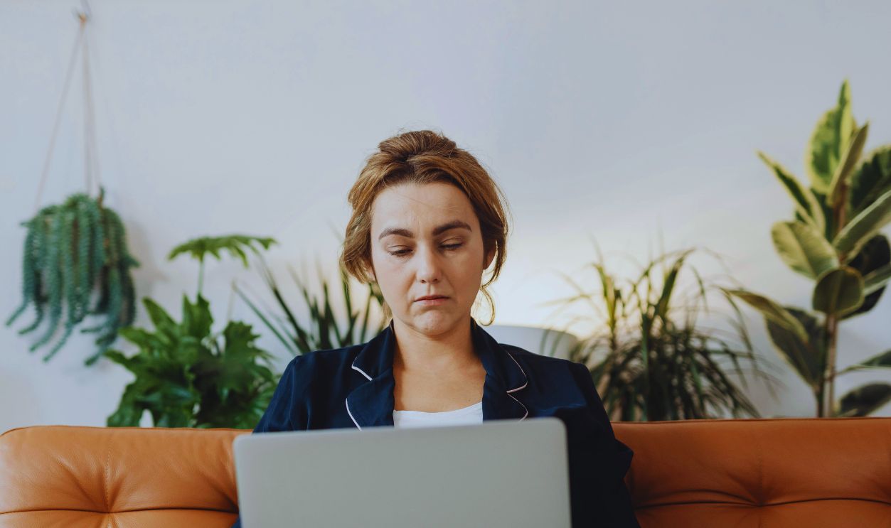 Woman Sitting on the Sofa with a Laptop on her Lap