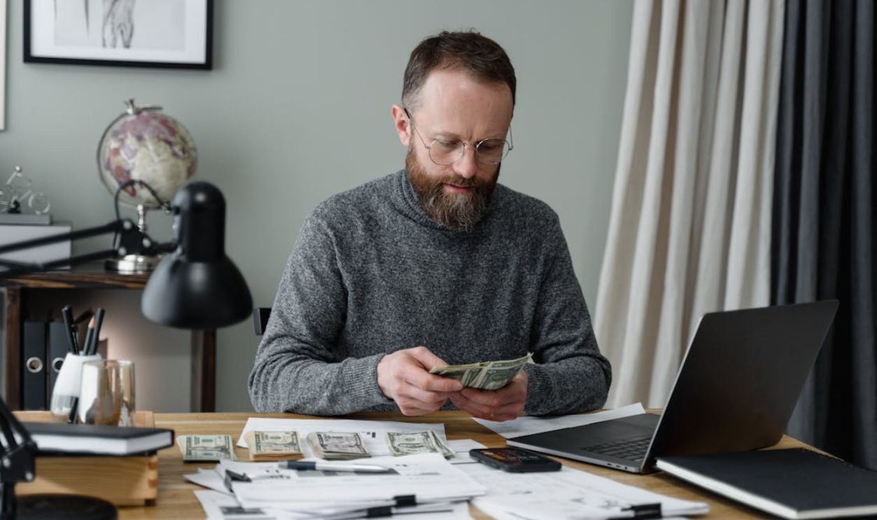 A Man in Gray Long Sleeves Shirt Counting Cash Money