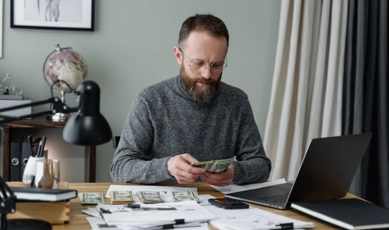 A Man in Gray Long Sleeves Shirt Counting Cash Money