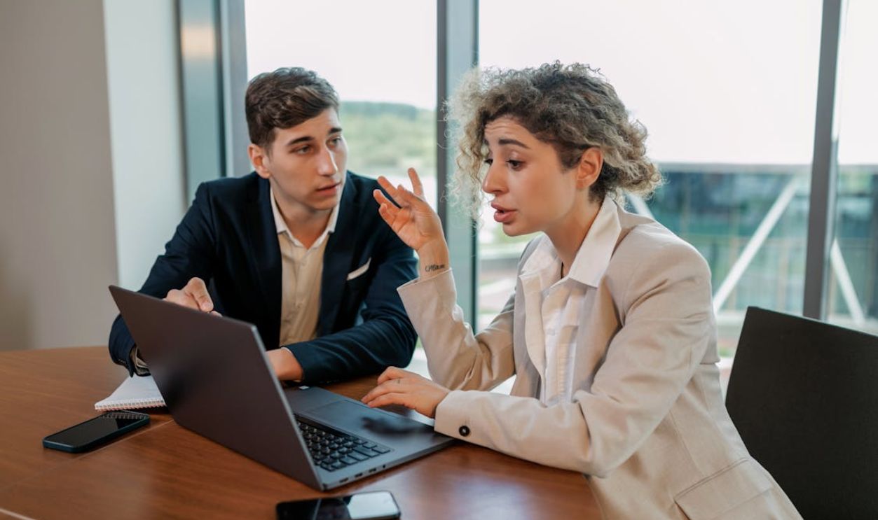 Businessman and Woman Sitting at Table with Laptop
