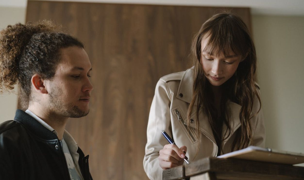 A Woman Signing a Document Beside a Man