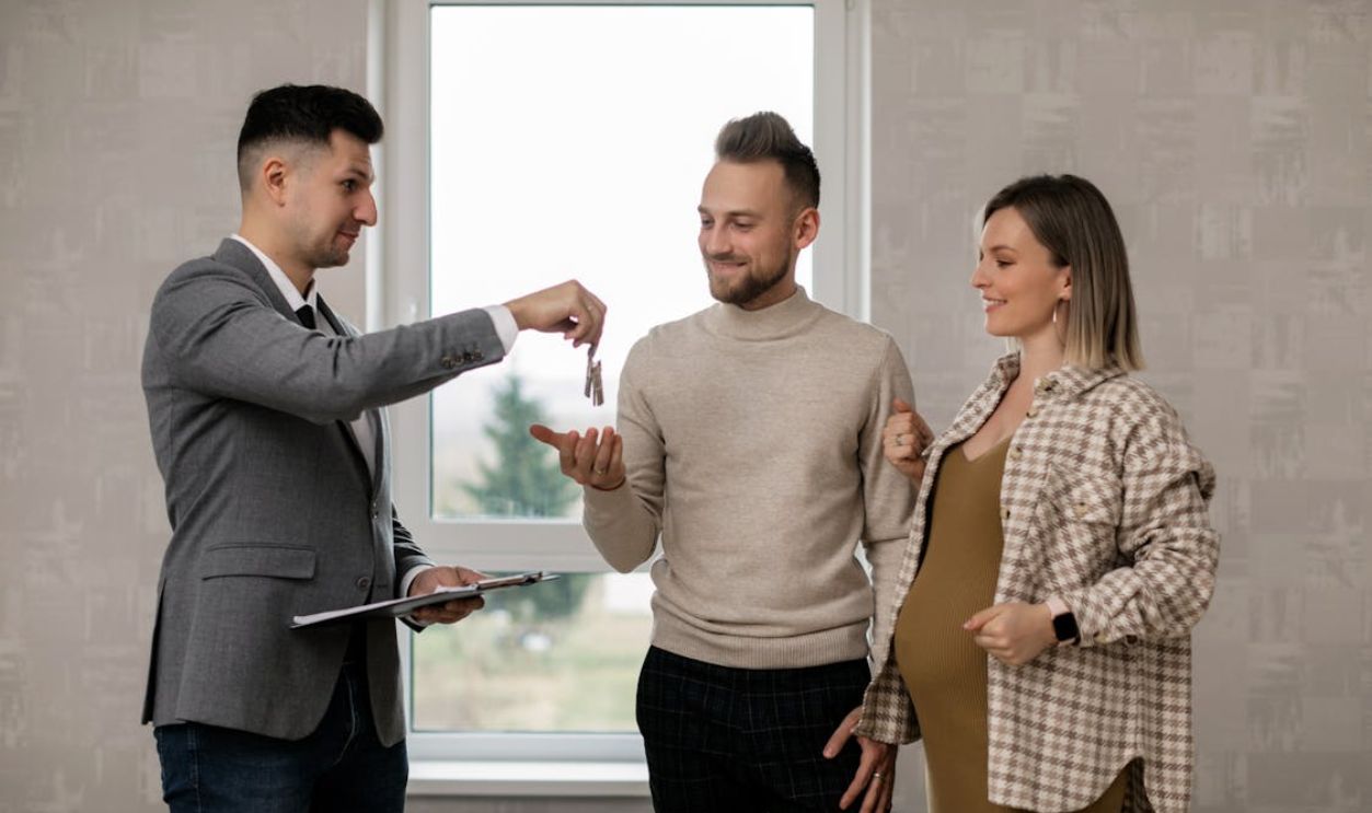 A Real Estate Agent Handing the Key to the New Homeowners