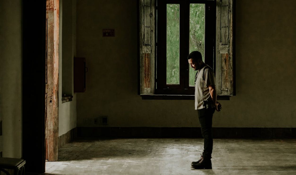A man standing in an empty room with a window