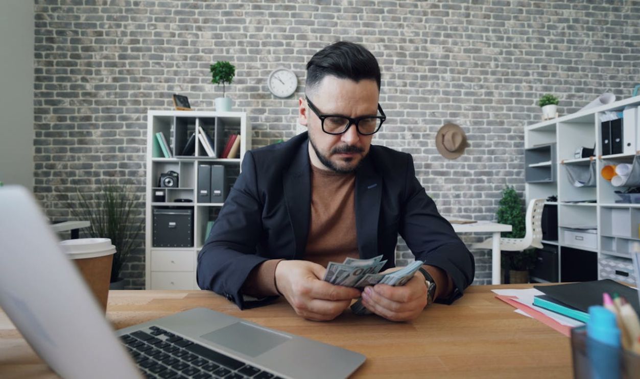 Happy Man Counting Money in Office