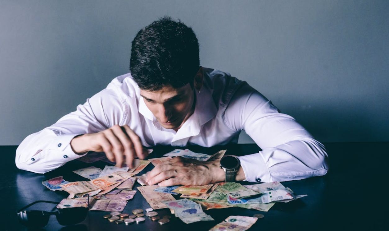 Man Counting International Currency on Desk